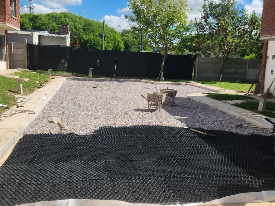 Calle interna de un complejo residencial en Las Piedras: dos operarias colocando las placas mientras se rellena el tramo terminado.