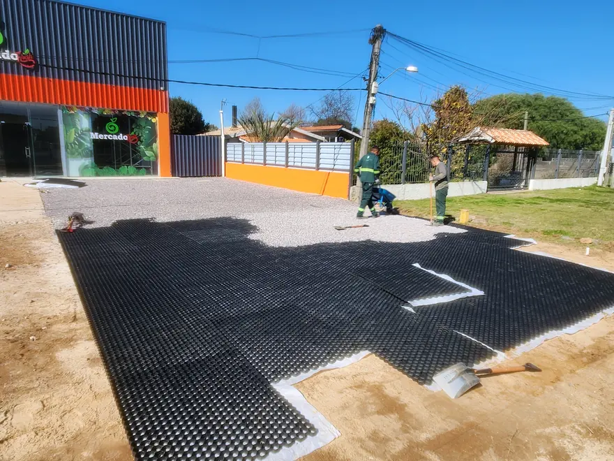 Estacionamiento de un local comercial en Solymar: la mitad de la superficie ya rellena con piedra y la otra mitad con las placas a la vista.